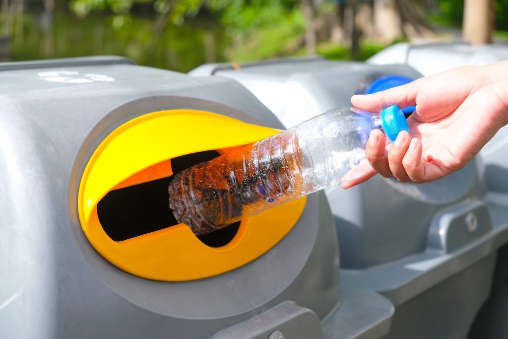 Please dispose of plastic bottle into the tank. A man throw rubbish in the trash can by separate garbage to dispose like hazardous waste ,