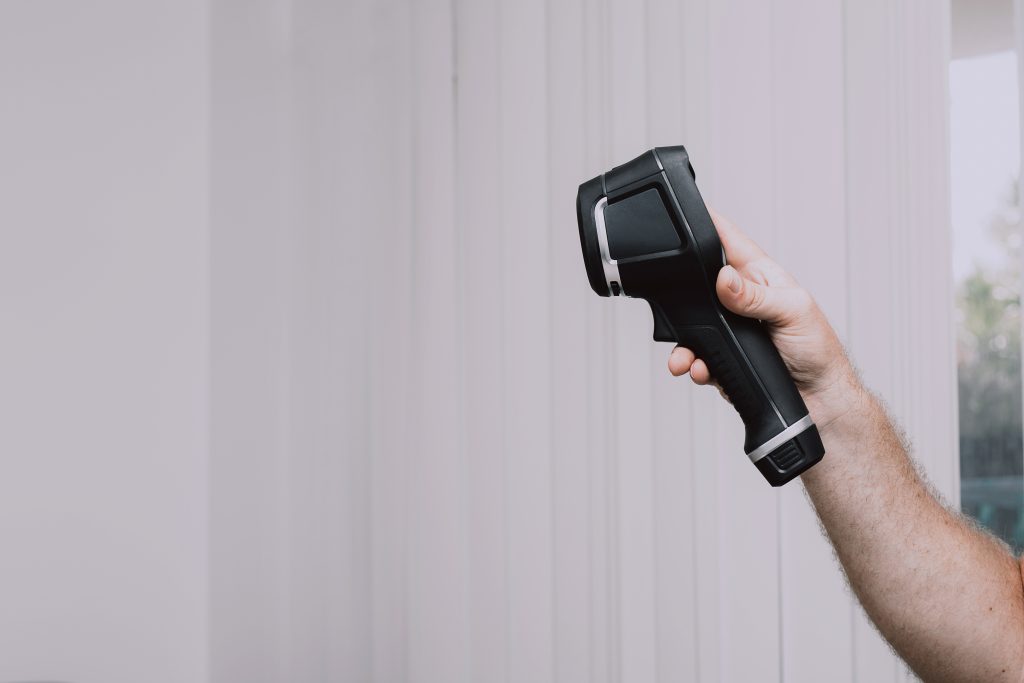 Male Pest Control Worker checking apartment with thermal imaging camera for termite detection, regular yearly check.