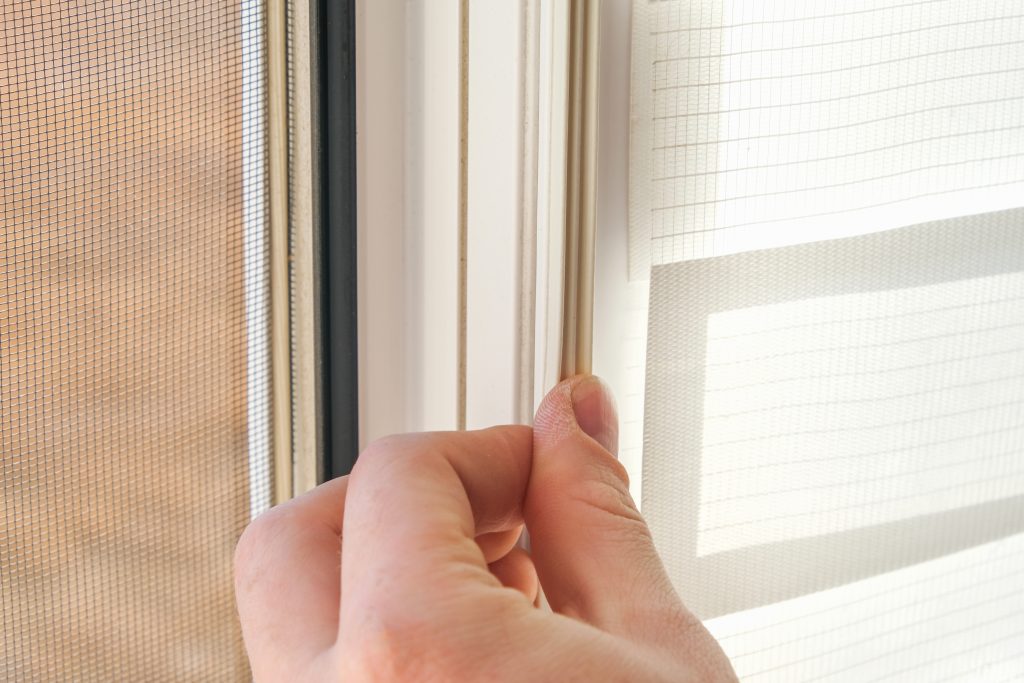 The man wipes the window frame with a degreaser and glues a sealing rubber tape on it for noise insulation, wind protection, weather protection.